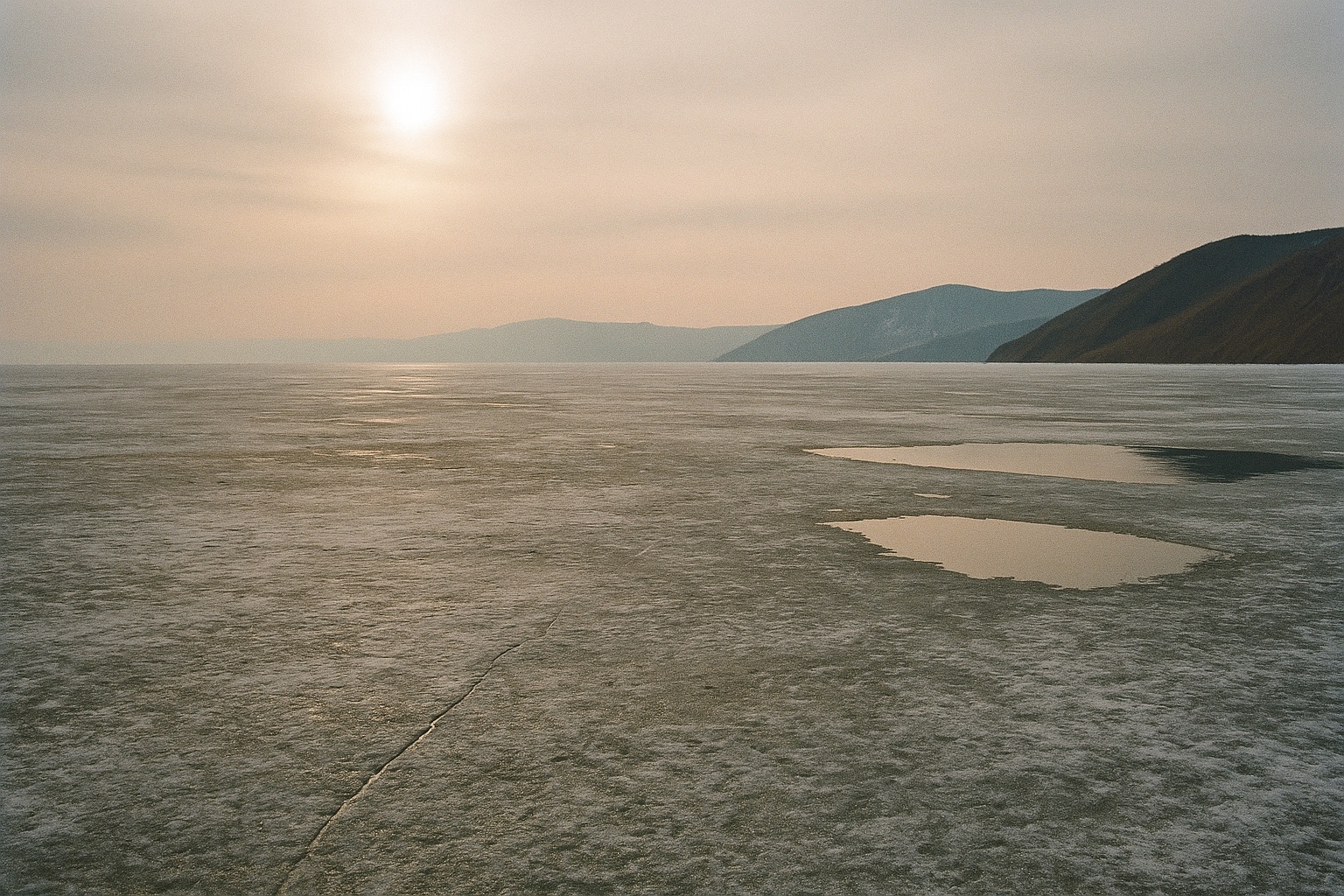 Graues, poröses Eis im März mit Flecken offenen Wassers und Schmelzwasser unter warmer Sonne