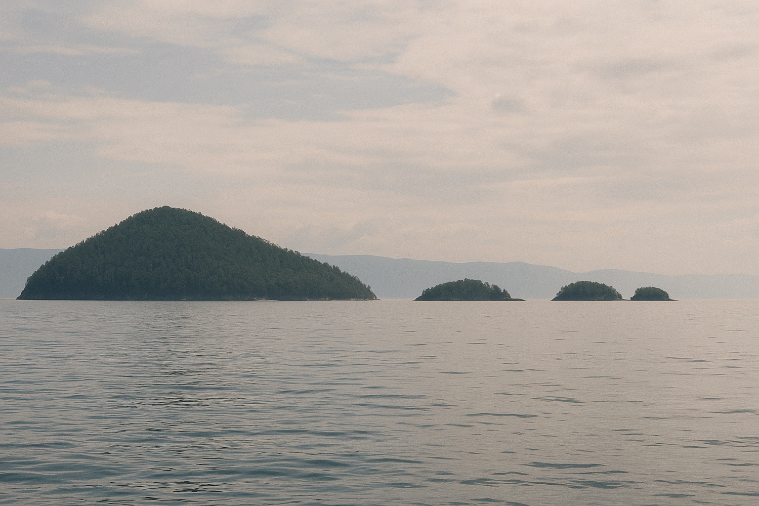 Eine größere bewaldete Insel und drei kleinere Inseln auf dem offenen See